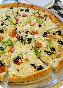 Fresh veggie pizza with green peppers, tomatoes, onions, mushrooms, and black olives.